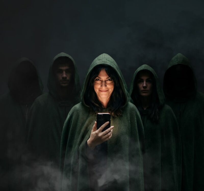 Five hooded Traitors players, one lit by her phone